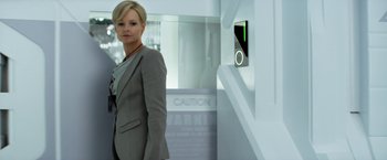 Movie still from “Elysium” (2013), directed by Neill Blomkamp – A woman in a suit standing in front of an elevator; Medium shot, Low angle
