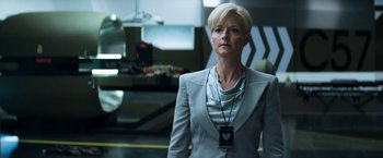 Movie still from “Elysium” (2013), directed by Neill Blomkamp – A woman with blonde hair wearing a gray suit; Medium shot, Low angle