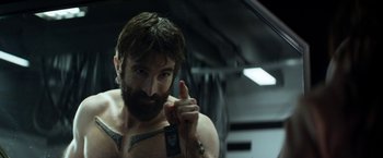 Movie still from “Elysium” (2013), directed by Neill Blomkamp – A man with a beard and a tattoo on his arm; Close Up shot, Over the shoulder angle