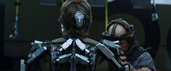 Movie still from “Elysium” (2013), directed by Neill Blomkamp – A man wearing a back brace with multiple attachments on his back; Close Up shot, Over the shoulder angle
