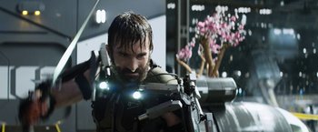 Movie still from “Elysium” (2013), directed by Neill Blomkamp – A man with a beard holding a gun in his hands; Medium shot, Low angle