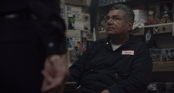 Movie still from “The Tax Collector” (2020), directed by David Ayer – An older man sitting in front of a woman; Medium shot, Over the shoulder angle