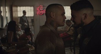 Movie still from “The Tax Collector” (2020), directed by David Ayer – A man with a tattoo on his face and a man with a beard on his head; Close Up shot, Over the shoulder angle