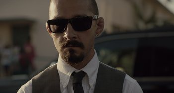 Movie still from “The Tax Collector” (2020), directed by David Ayer – A person wearing a suit and sunglasses; Close Up shot, Low angle