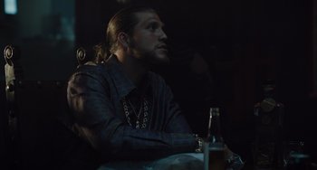 Movie still from “The Tax Collector” (2020), directed by David Ayer – A man sitting at a table with a bottle of beer; Close Up shot, Low angle