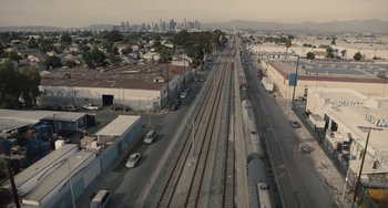 Movie still from “The Tax Collector” (2020), directed by David Ayer – An aerial view of a train track in the middle of a city; Extreme Wide shot, High angle