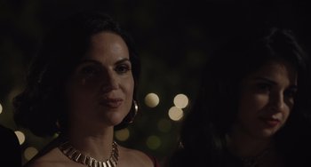 Movie still from “The Tax Collector” (2020), directed by David Ayer – A person wearing a necklace with lights in the background; Close Up shot, Over the shoulder angle