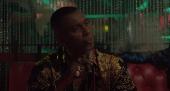 Movie still from “The Tax Collector” (2020), directed by David Ayer – A man smoking a cigarette while wearing a gold jacket; Close Up shot, Over the shoulder angle