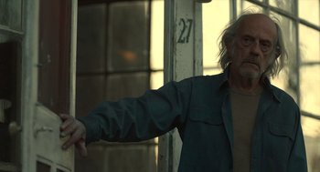 Movie still from “The Tender Bar” (2021), directed by George Clooney – An older man pointing at something in the distance; Medium shot, Low angle