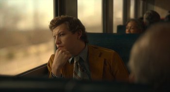 Movie still from “The Tender Bar” (2021), directed by George Clooney – A man sitting in a chair with his hand under his chin; Medium shot, Over the shoulder angle