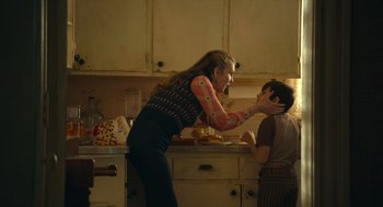Movie still from “The Tender Bar” (2021), directed by George Clooney – A woman and a boy in a kitchen; Medium shot, Low angle