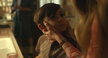 Movie still from “The Tender Bar” (2021), directed by George Clooney – A young boy with his hand on his face; Close Up shot, Over the shoulder angle