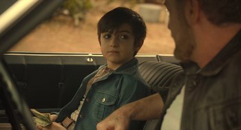 Movie still from “The Tender Bar” (2021), directed by George Clooney – A young boy sitting in the back seat of a car; Close Up shot, Over the shoulder angle