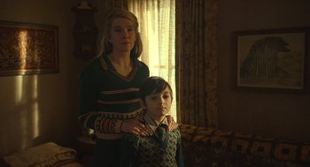 Movie still from “The Tender Bar” (2021), directed by George Clooney – A woman standing next to a young boy in a room; Medium shot, Low angle
