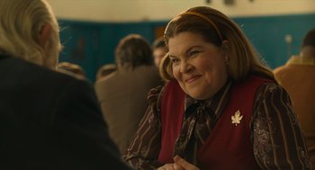 Movie still from “The Tender Bar” (2021), directed by George Clooney – A woman sitting in front of a group of people; Close Up shot, Over the shoulder angle