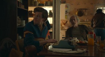 Movie still from “The Tender Bar” (2021), directed by George Clooney – A man sitting at a table with an older man; Medium shot, Over the shoulder angle