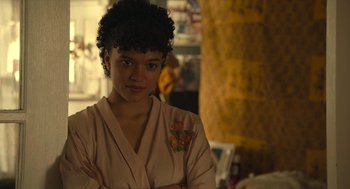 Movie still from “The Tender Bar” (2021), directed by George Clooney – A young woman with her arms crossed in a room; Close Up shot, Over the shoulder angle