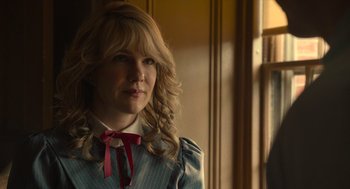 Movie still from “The Tender Bar” (2021), directed by George Clooney – A woman with blonde curly hair wearing a blue dress; Close Up shot, Over the shoulder angle