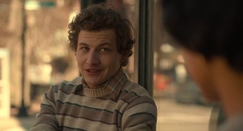 Movie still from “The Tender Bar” (2021), directed by George Clooney – A young man with curly brown hair wearing a striped sweater; Close Up shot, Over the shoulder angle