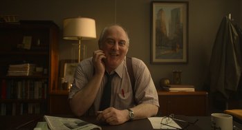 Movie still from “The Tender Bar” (2021), directed by George Clooney – An older man sitting at a table with a phone to his ear; Medium shot, Low angle