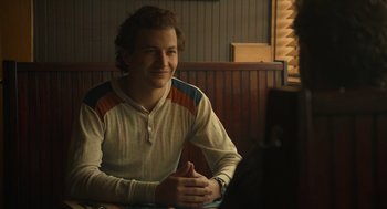 Movie still from “The Tender Bar” (2021), directed by George Clooney – A man sitting in front of a computer in a restaurant; Medium shot, Over the shoulder angle