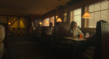 Movie still from “The Tender Bar” (2021), directed by George Clooney – People sitting at a booth in a restaurant eating and drinking orange juice; Wide shot, High angle