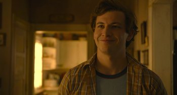 Movie still from “The Tender Bar” (2021), directed by George Clooney – A young man smiling for the camera while wearing a plaid shirt; Close Up shot, Over the shoulder angle