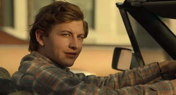 Movie still from “The Tender Bar” (2021), directed by George Clooney – A young man driving a car with a side view mirror; Close Up shot, Over the shoulder angle