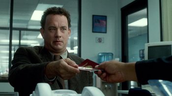 Movie still from “The Terminal” (2004), directed by Steven Spielberg – A man in a suit and tie holding a passport; Close Up shot, Over the shoulder angle