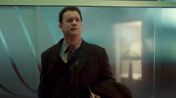 Movie still from “The Terminal” (2004), directed by Steven Spielberg – A man in a suit and tie holding a bag; Medium shot, Low angle
