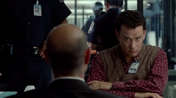Movie still from “The Terminal” (2004), directed by Steven Spielberg – A man sitting in front of a group of people; Close Up shot, Over the shoulder angle