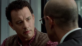 Movie still from “The Terminal” (2004), directed by Steven Spielberg – A man in a brown sweater is talking to another man in glasses; Close Up shot, Over the shoulder angle