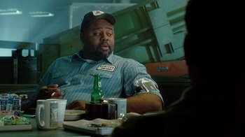 Movie still from “The Terminal” (2004), directed by Steven Spielberg – A man sitting at a table with a bottle of beer in front of him; Medium shot, Over the shoulder angle