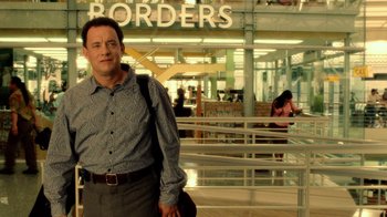 Movie still from “The Terminal” (2004), directed by Steven Spielberg – A man standing in front of an airport with luggage; Medium shot, Low angle
