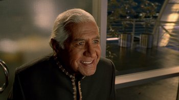Movie still from “The Terminal” (2004), directed by Steven Spielberg – An older man with white hair smiling for the camera; Close Up shot, Over the shoulder angle