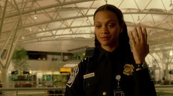 Movie still from “The Terminal” (2004), directed by Steven Spielberg – A police officer in uniform holding up a peace sign; Medium shot, Over the shoulder angle