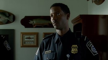 Movie still from “The Terminal” (2004), directed by Steven Spielberg – A police officer is standing in front of a wall with fish on it; Close Up shot, Low angle