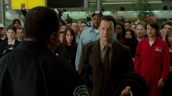 Movie still from “The Terminal” (2004), directed by Steven Spielberg – A crowd of people standing in a room; Medium shot, Over the shoulder angle