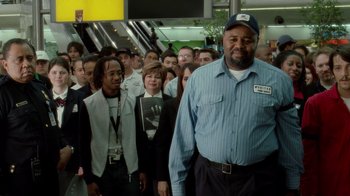Movie still from “The Terminal” (2004), directed by Steven Spielberg – A group of people standing in a line; Medium shot, Low angle