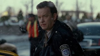 Movie still from “The Terminal” (2004), directed by Steven Spielberg – A man in a black jacket standing next to a street; Close Up shot, Over the shoulder angle