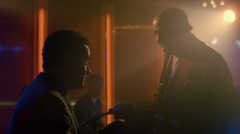 Movie still from “The Terminal” (2004), directed by Steven Spielberg – Two men are talking in a dimly - lit room; Medium shot, Over the shoulder angle