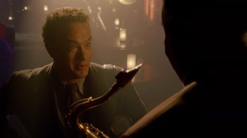 Movie still from “The Terminal” (2004), directed by Steven Spielberg – A man in a suit and tie holding a saxophone; Close Up shot, Over the shoulder angle
