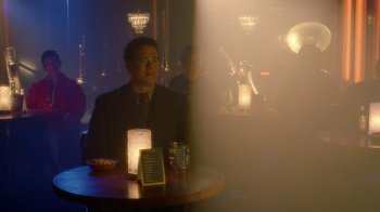 Movie still from “The Terminal” (2004), directed by Steven Spielberg – A man sitting at a table in front of a candle; Medium shot, Over the shoulder angle