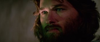 Movie still from “The Thing” (1982), directed by John Carpenter – A person with a beard and green eyes; Close Up shot, Low angle