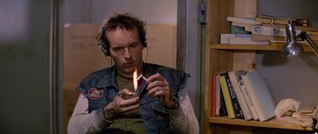 Movie still from “The Thing” (1982), directed by John Carpenter – A man with headphones on holding a lit cigarette; Close Up shot, High angle