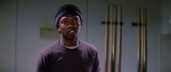 Movie still from “The Thing” (1982), directed by John Carpenter – A young man wearing a headband in a room; Close Up shot, Low angle