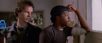 Movie still from “The Thing” (1982), directed by John Carpenter – Two men in a living room one of whom is wearing a head band; Close Up shot, Low angle