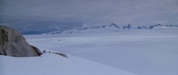 Movie still from “The Thing” (1982), directed by John Carpenter – A person is skiing on a snowy slope; Extreme Wide shot, High angle