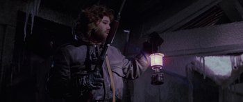 Movie still from “The Thing” (1982), directed by John Carpenter – A man holding a lantern in a dark room; Medium shot, Low angle