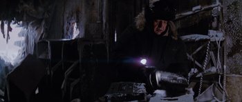 Movie still from “The Thing” (1982), directed by John Carpenter – A man working with a flashlight in an industrial setting; Medium shot, Low angle